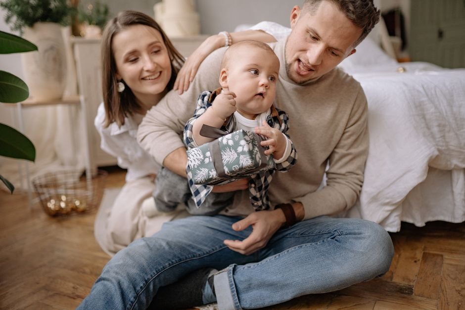 Young parents sitting on a living-room floor with their baby