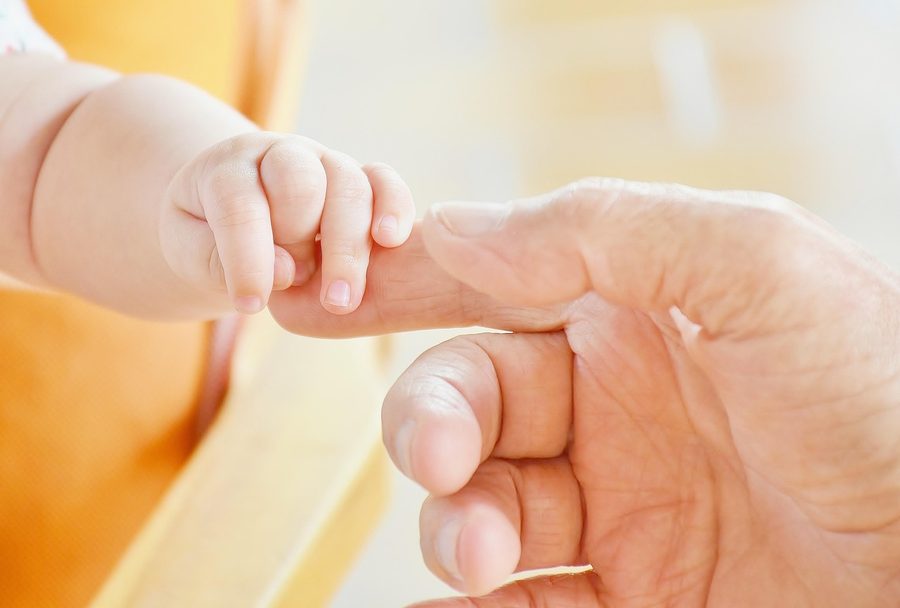 A baby's hand holding an adult finger